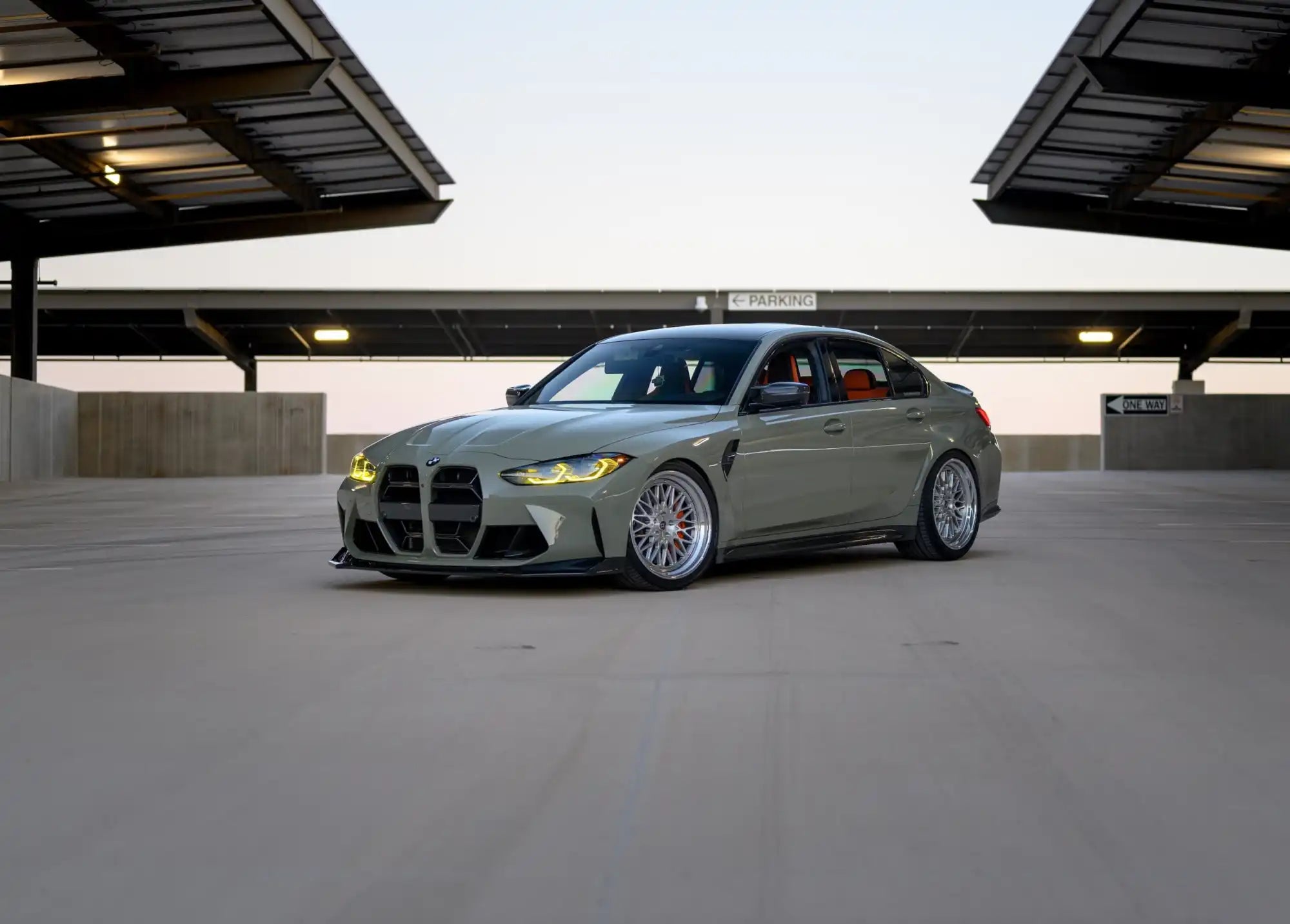 Matte grey sports sedan with custom multi-spoke wheels and amber daytime running lights.